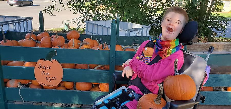 A member laughing with joy next to a wagon full of pumpkins