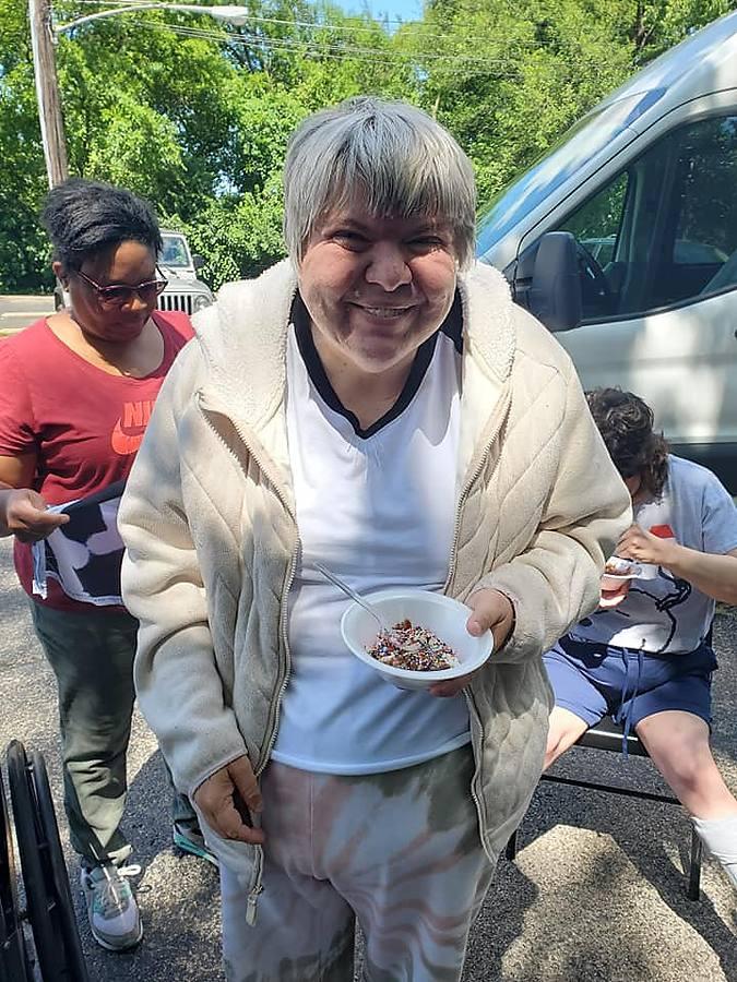 A member smiling and holding an ice cream sundae she made