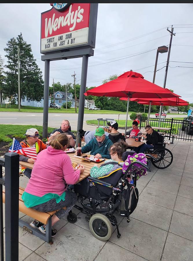 Members enjoying lunch together on a restaurant patio under red umbrellas