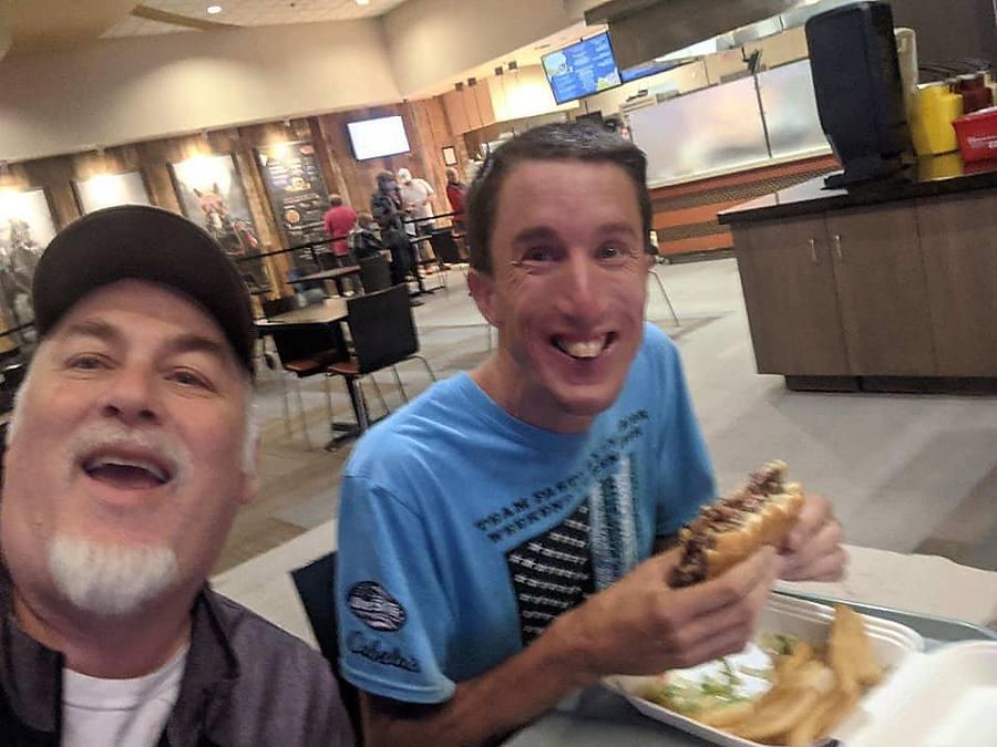 A member and staff selfie over burgers and fries