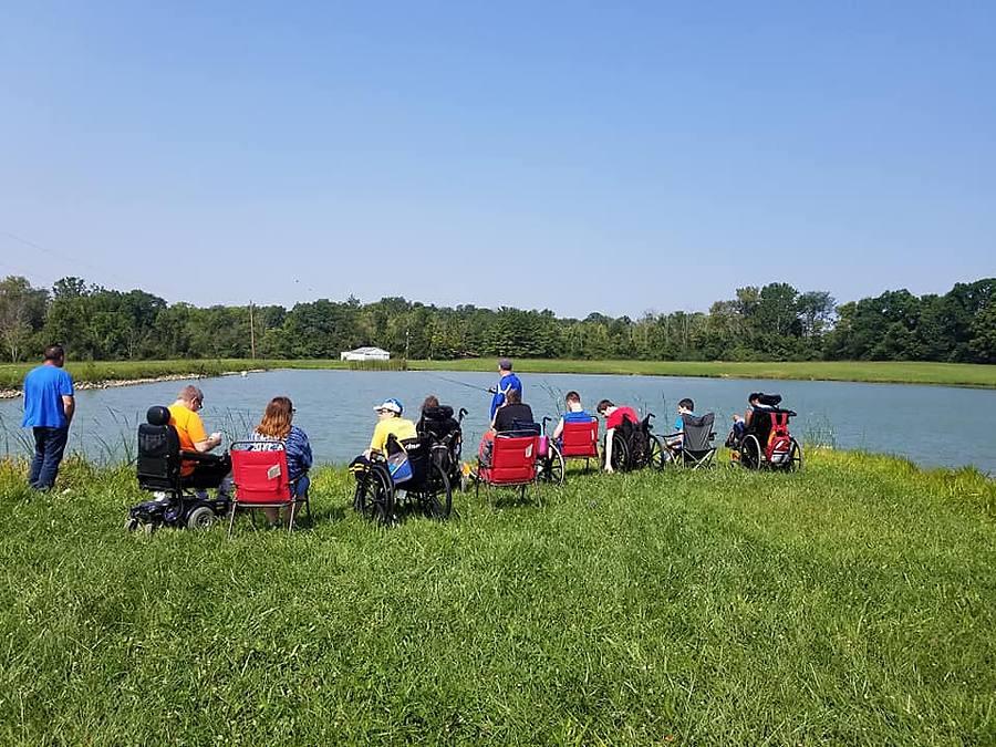 A group of members fishing together at the edge of a pond