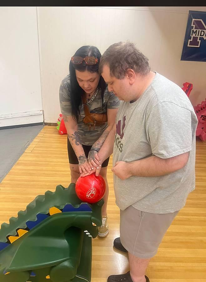 A staff member and member bowling together using a ramp