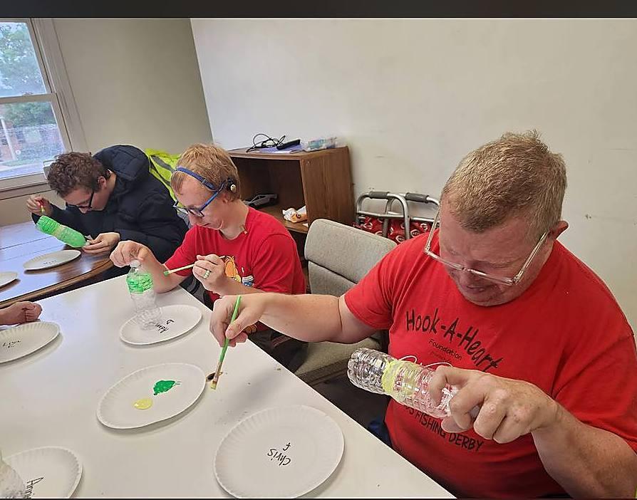 Members painting water bottles at a craft table