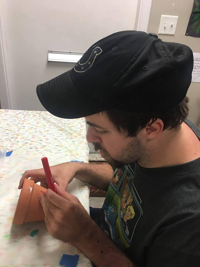 A member carefully decorating a flower pot
