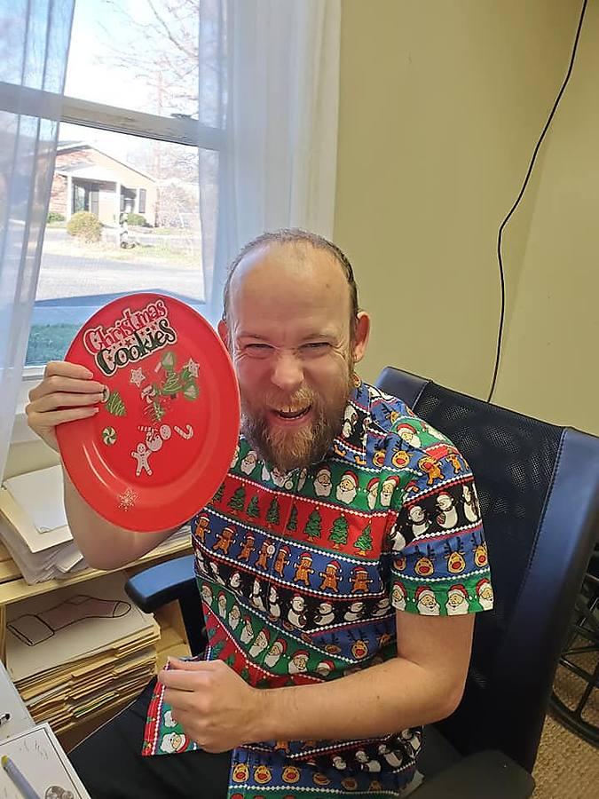 A member in a festive shirt showing off a Christmas cookies plate