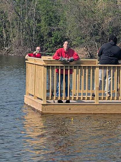 Members fishing off a wooden dock on a sunny day