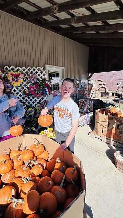 A member smiling big while painting a pumpkin