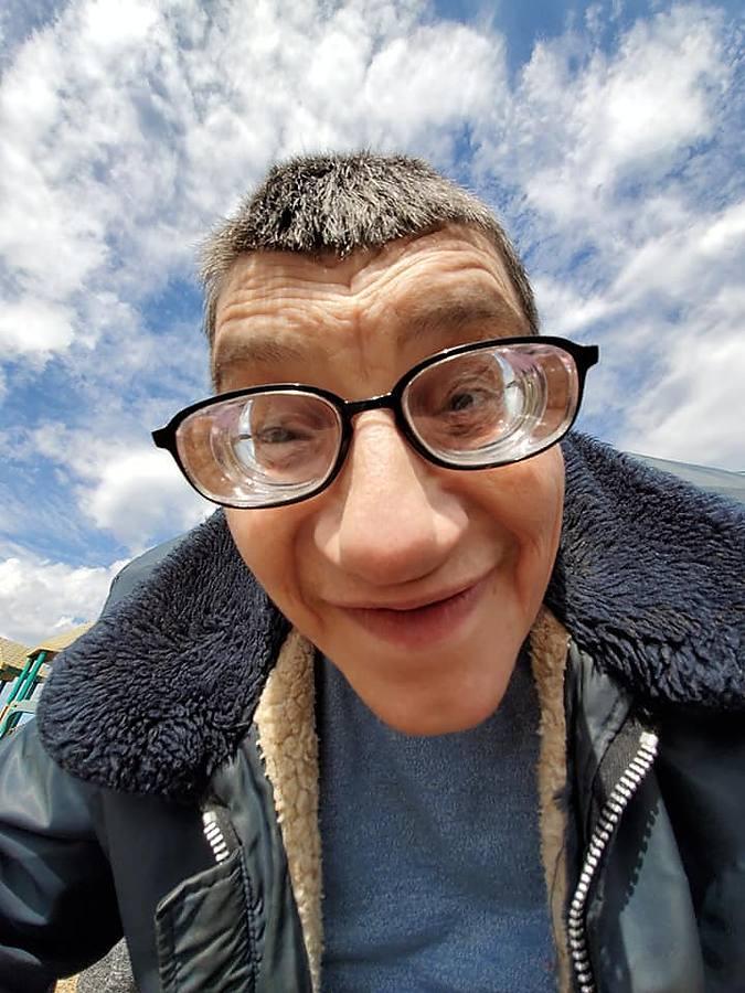 A member grinning ear to ear in a closeup selfie under a blue sky