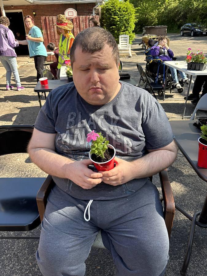 A member laughing while holding a flower he planted