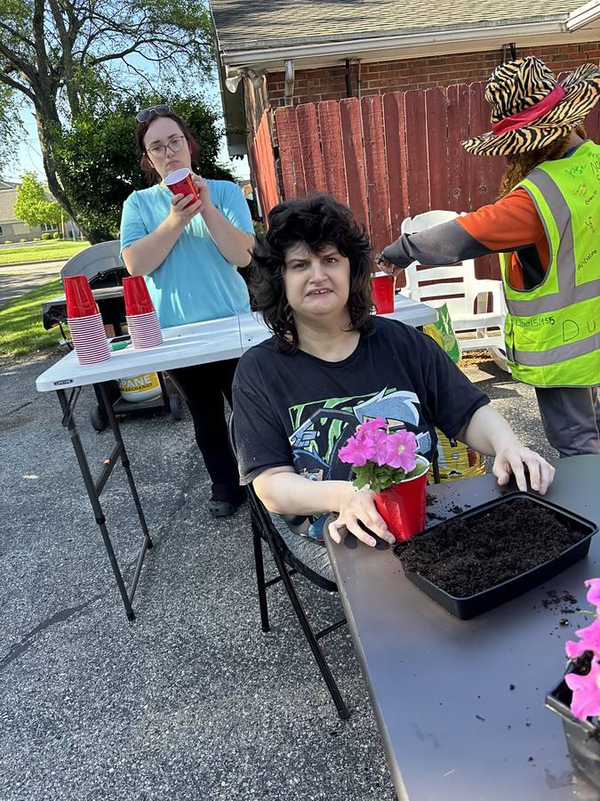 A member proudly showing her painted pink hand next to the Companions handprint board