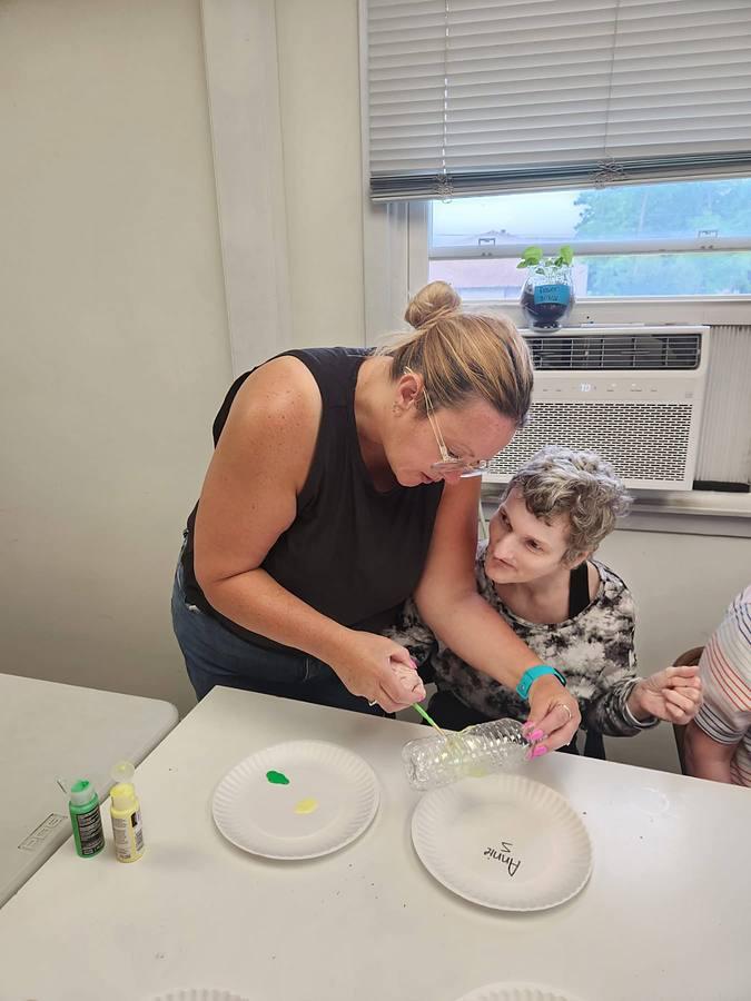 A staff member helping a member paint during craft time